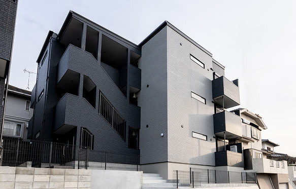 福岡の空の下に佇む、モノトーンでスタイリッシュなデザインの新築アパートです。